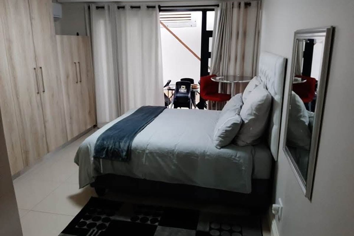 A well-maintained bedroom featuring built-in cupboards, tiled flooring, and a sliding door providing access to an outdoor area.