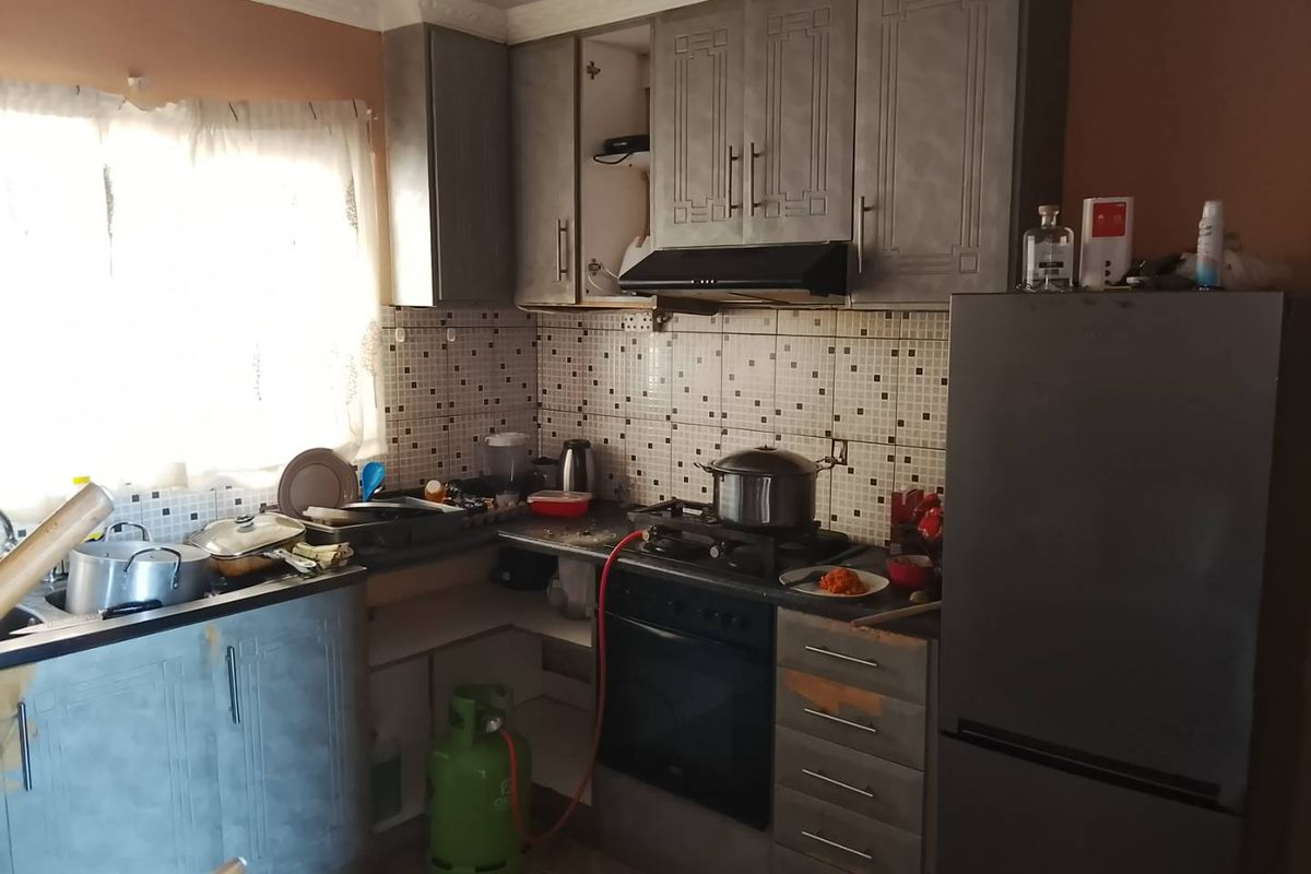 A functional kitchen featuring built-in cabinetry, a gas hob with extractor fan, and tiled backsplash, requiring some maintenance and cosmetic updates.