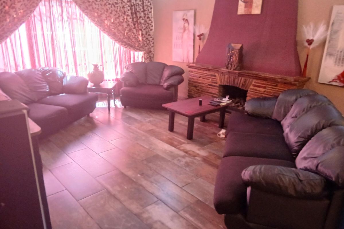 A living room featuring a prominent stone-clad fireplace and tiled flooring, offering a cozy space for relaxation.