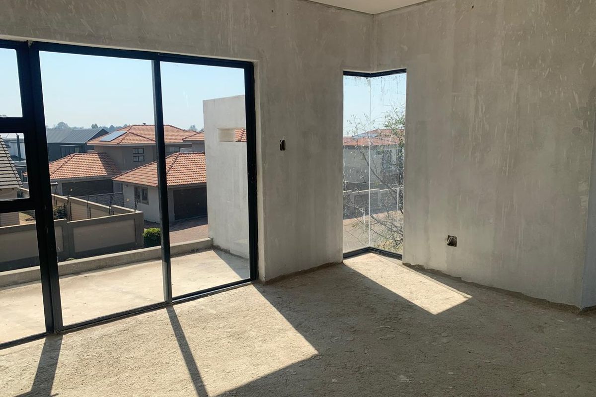 An unfinished bedroom interior featuring plastered walls, cement screed flooring, and large sliding glass doors leading to an outdoor area.