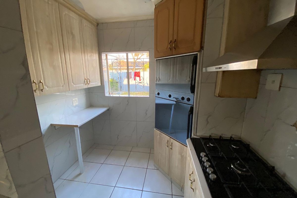 A compact kitchen featuring built-in cabinetry, a gas hob, an integrated oven, and tiled finishes throughout, offering a functional space ready for modernization.