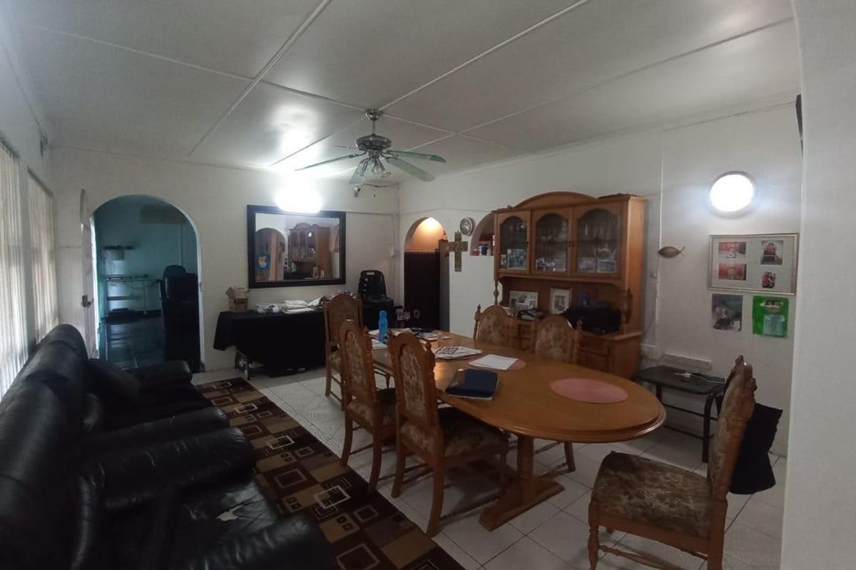 A dated living and dining area featuring tiled flooring, a ceiling fan, and arched doorways leading to adjacent rooms.