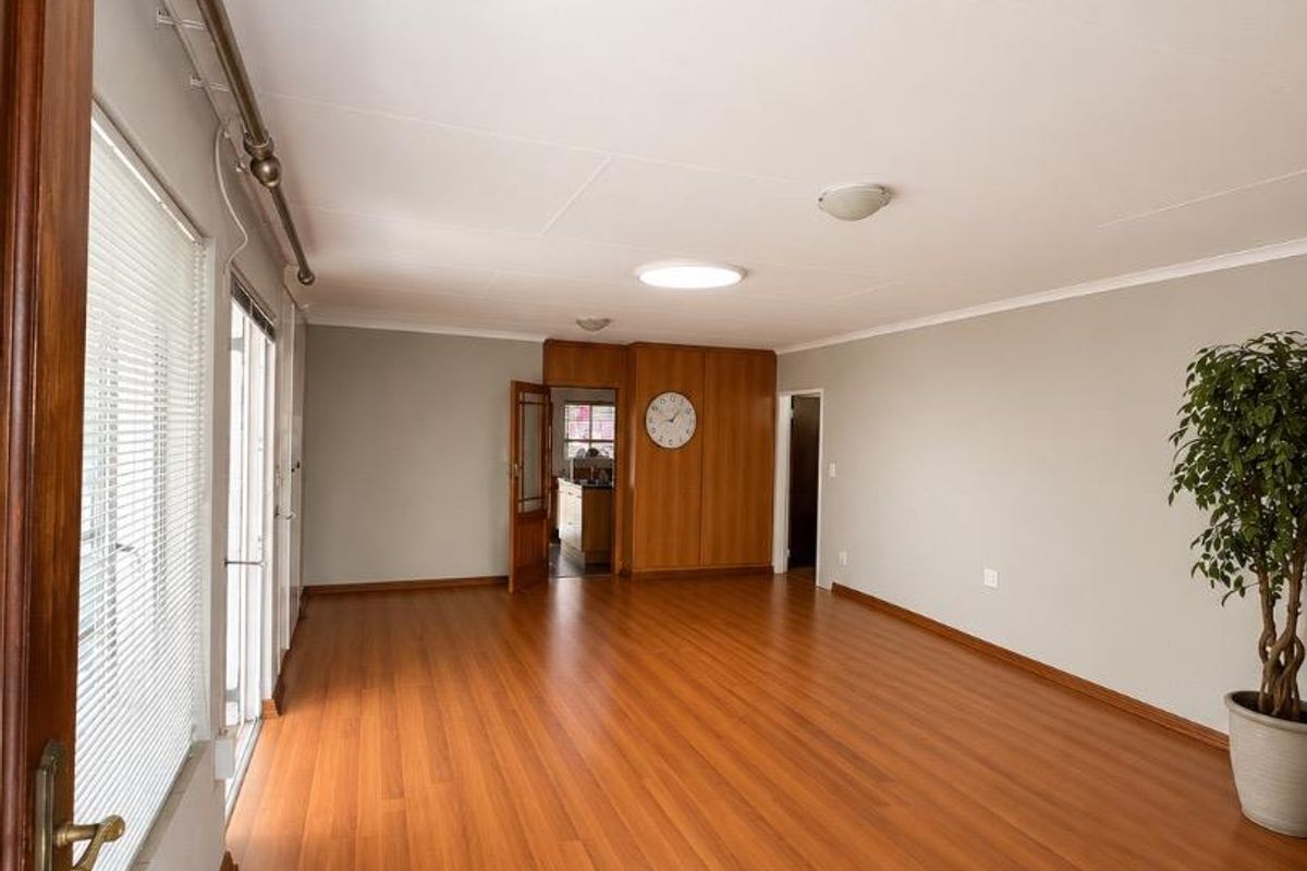 Spacious living area featuring warm-toned laminate flooring, wood paneling accents, and sliding glass doors providing natural light.