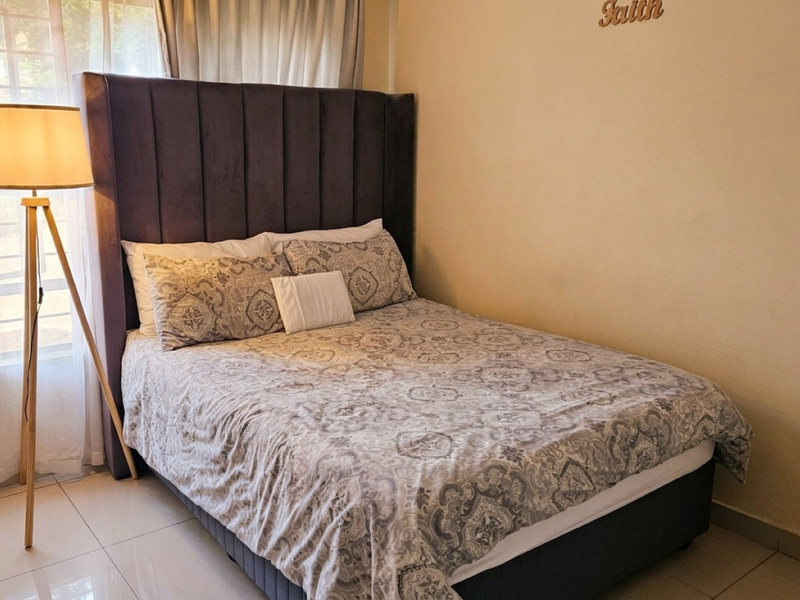 A bedroom featuring tiled flooring and a window fitted with security bars.
