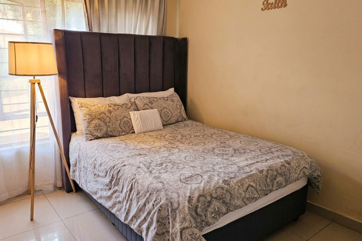 A bedroom featuring tiled flooring and a window fitted with security bars.