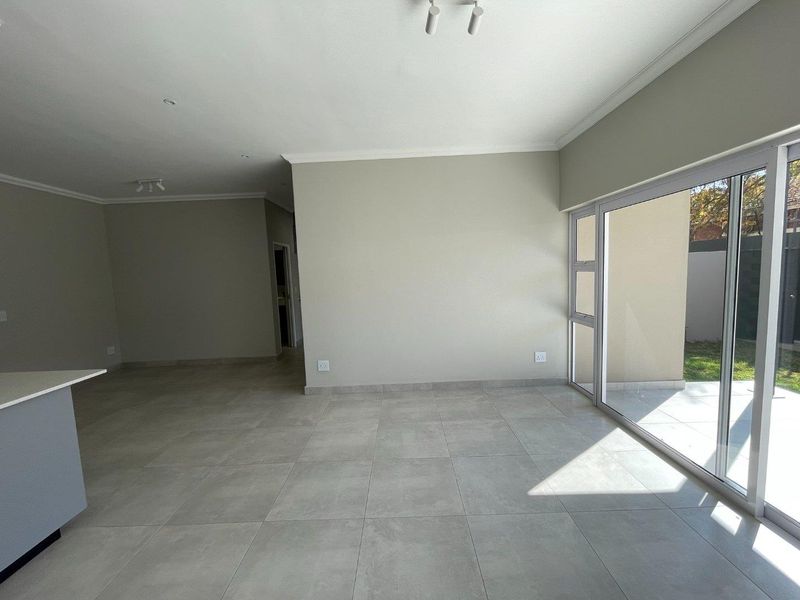 Spacious open-plan living area featuring neutral tiled flooring, modern recessed lighting, and large sliding glass doors providing access to the outdoor space.