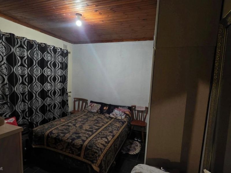 A bedroom featuring a timber ceiling, tiled flooring, and a built-in wardrobe, offering a functional space with potential for modern updates.
