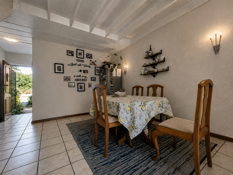 A dining area featuring tiled flooring and an exposed beam ceiling, with direct access to the exterior through a side door.