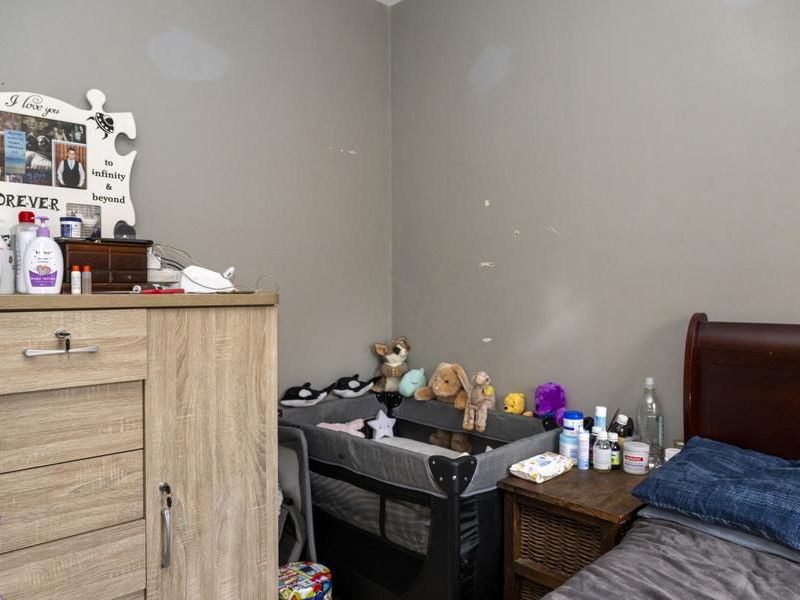A bedroom featuring neutral wall tones, providing a functional space for rest and storage.