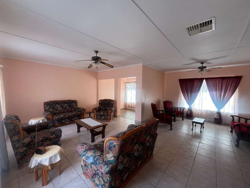 Spacious living area featuring neutral tiled flooring, ceiling fans, and air conditioning vents, offering a versatile layout for comfortable family living.