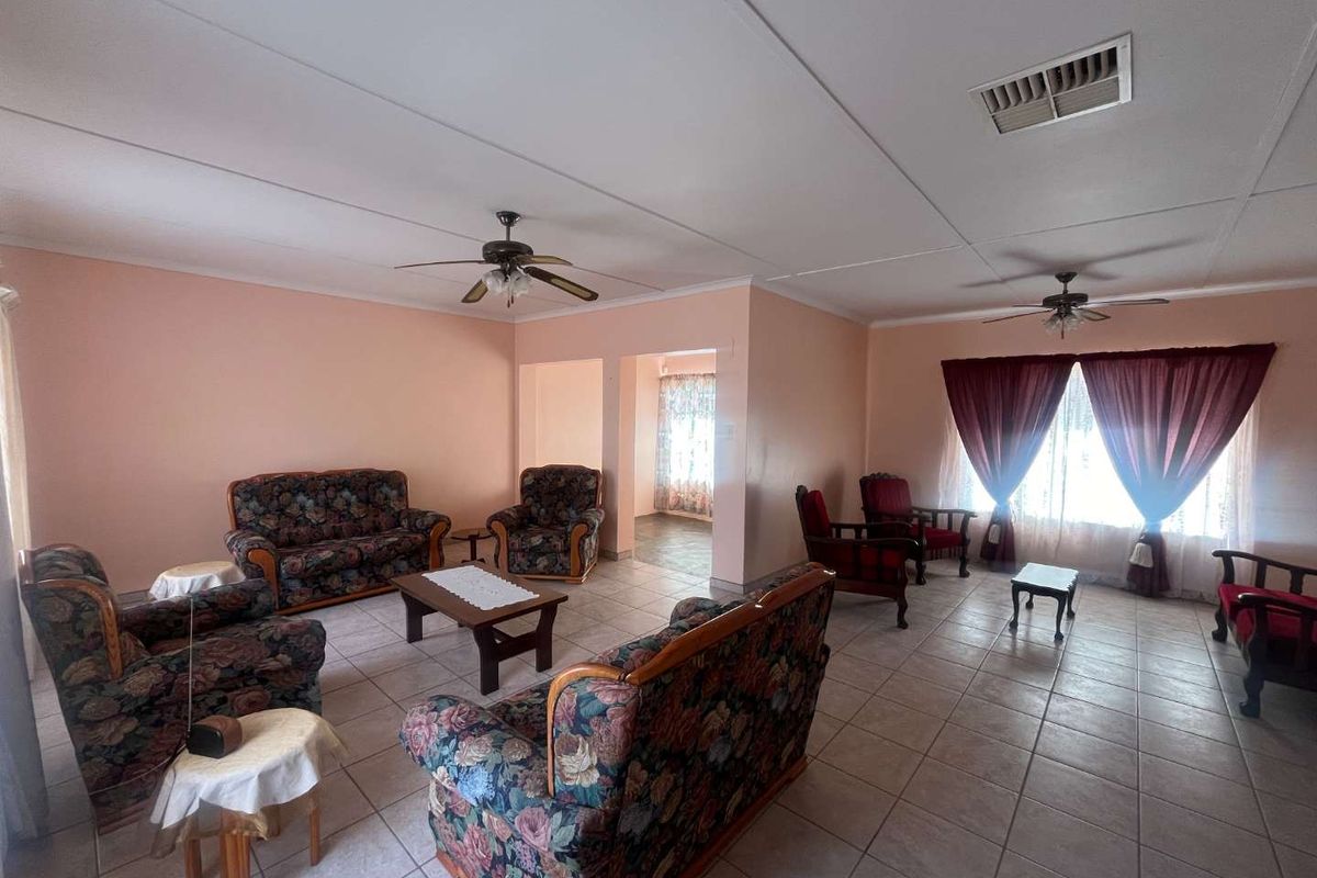 Spacious living area featuring neutral tiled flooring, ceiling fans, and air conditioning vents, offering a versatile layout for comfortable family living.