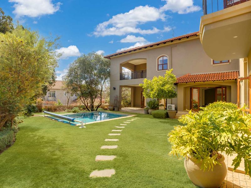 A well-maintained rear garden featuring a swimming pool, stone pathway, and a covered patio area attached to the double-story residence.