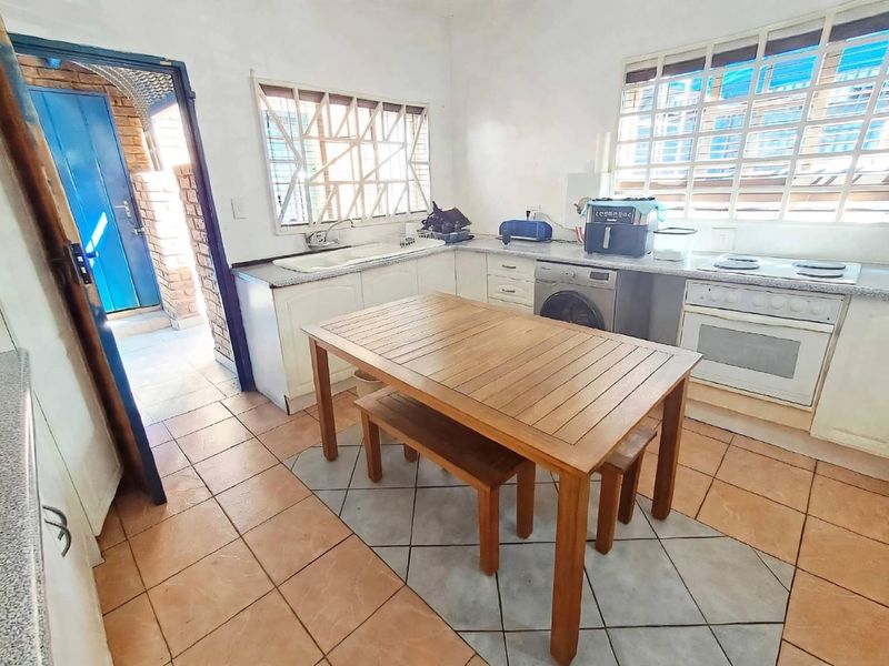 Functional kitchen featuring built-in cabinetry, integrated oven, hob, and double sink, with tiled flooring and security bars on windows.