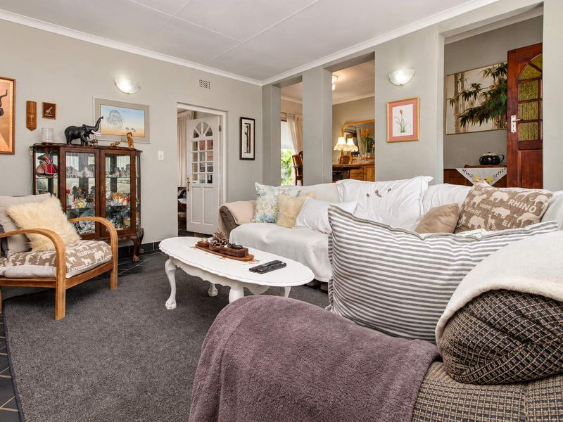 A comfortable living room featuring a mix of tiled and carpeted flooring, coved ceilings, and wall sconce lighting, with access to adjacent living spaces.