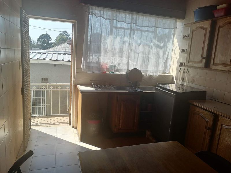 A functional kitchen featuring built-in wooden cabinetry, tiled walls, and direct access to an outdoor balcony area.