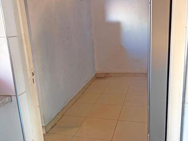 A vacant scullery or laundry area featuring tiled flooring and a coved ceiling, offering a functional space for utility needs.
