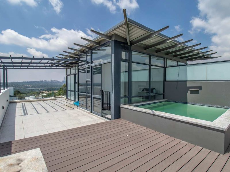 Spacious penthouse terrace featuring a private plunge pool, timber decking, modern pergola structure, and expansive city views through floor-to-ceiling glass walls.