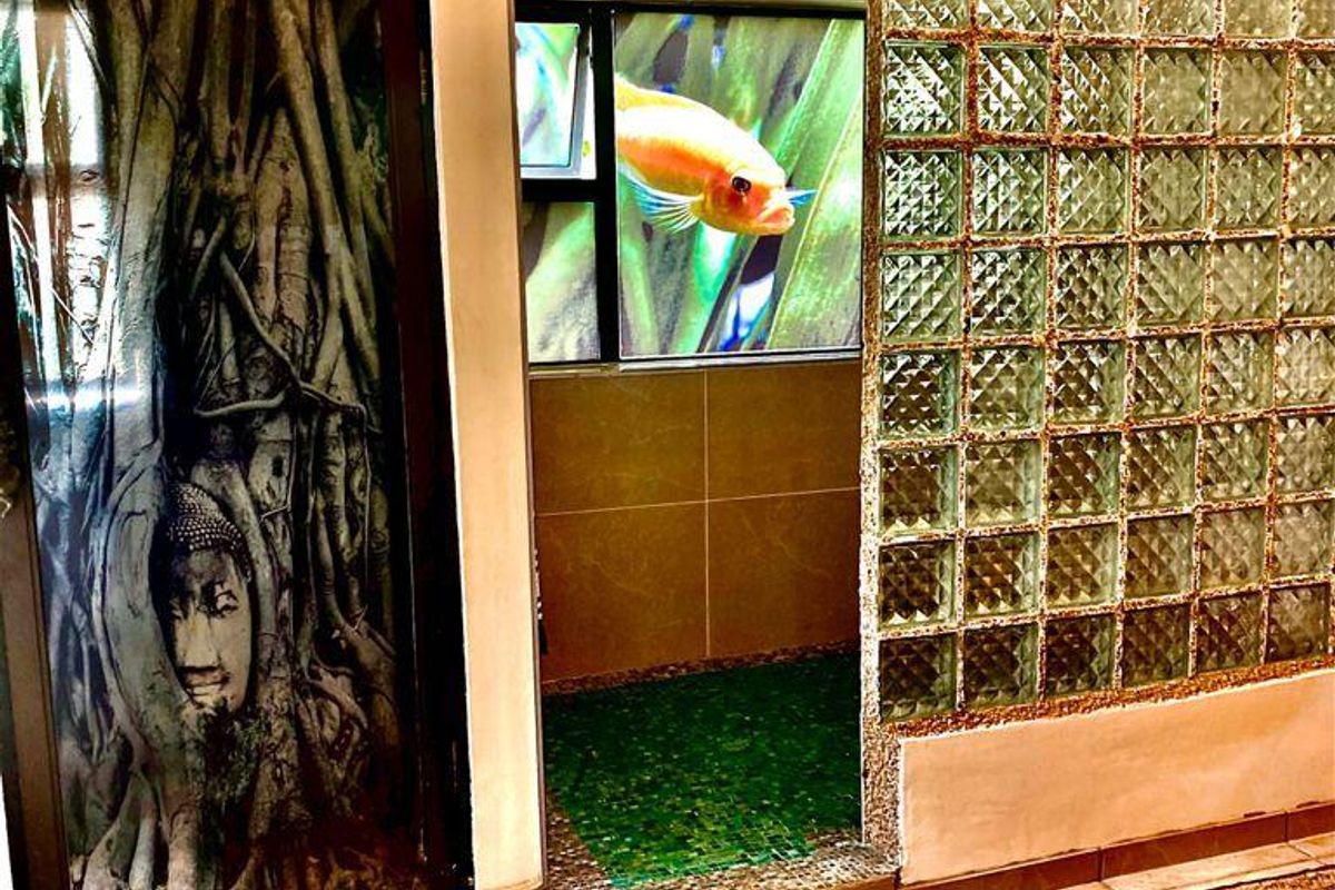 A unique bathroom space featuring a glass block partition, mosaic tiled flooring, and decorative wall art elements.