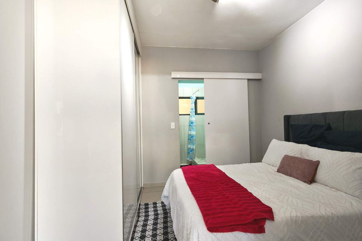 A bedroom featuring a built-in wardrobe and a sliding door leading to an en-suite bathroom area.