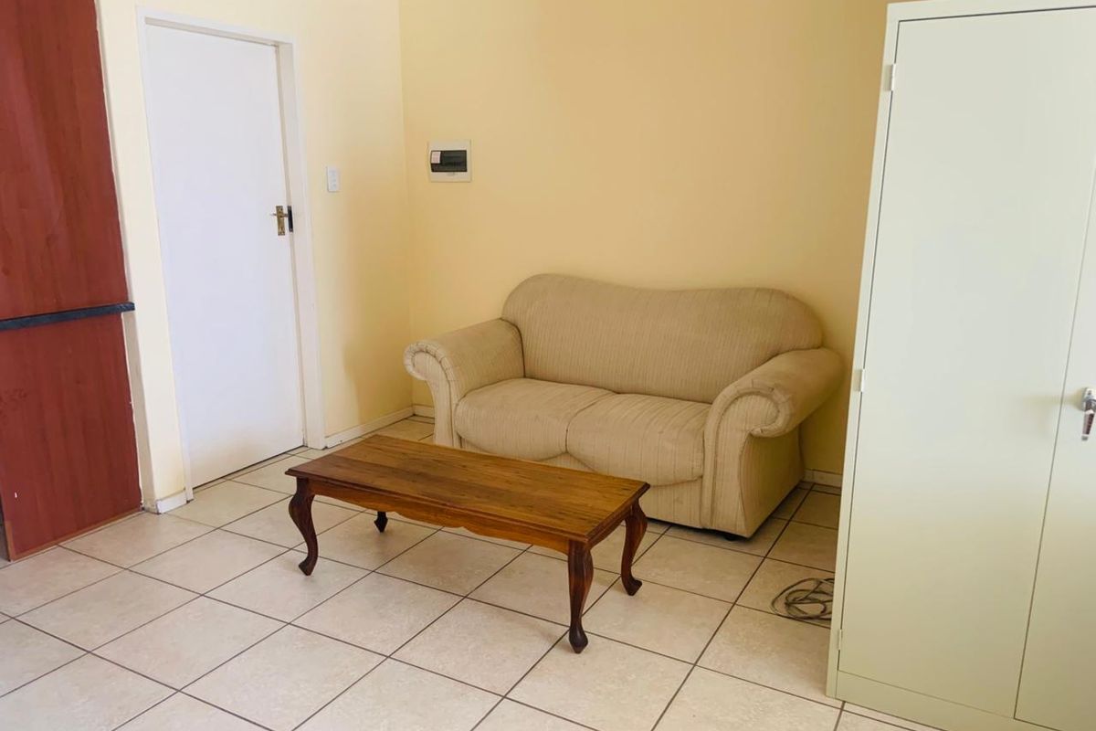 A simple living area featuring neutral wall paint and ceramic floor tiles, providing a functional and blank canvas for personalization.