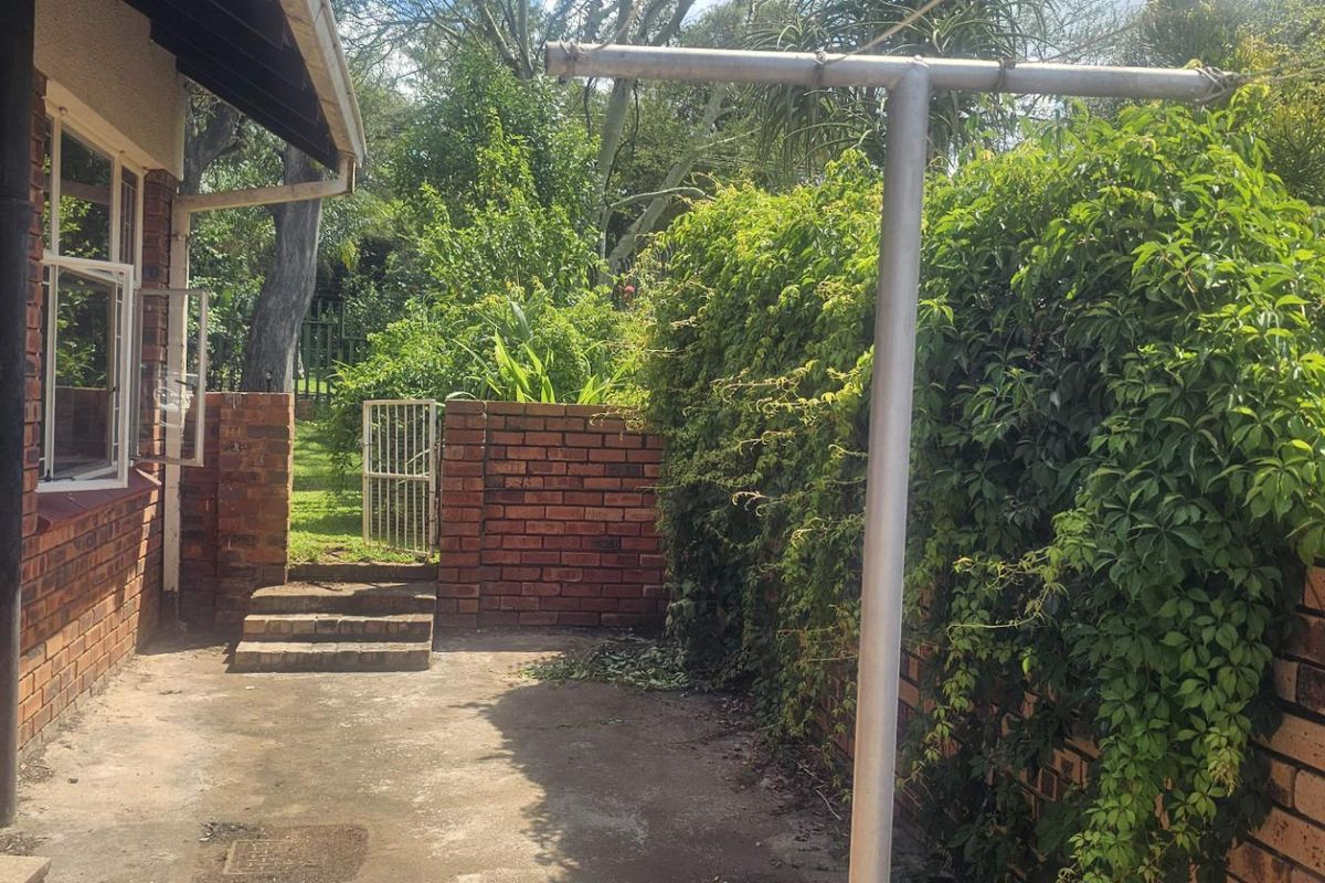 A private rear courtyard featuring brick boundary walls, concrete paving, and direct access to the garden area.