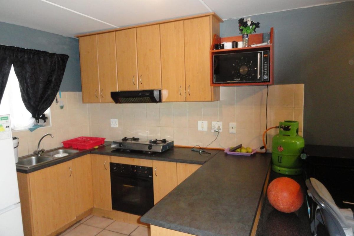 A functional kitchen featuring light wood cabinetry, a built-in oven, gas hob, extractor fan, and a tiled backsplash with ample countertop workspace.