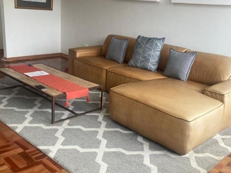 A comfortable living room area featuring classic parquet wood flooring and neutral wall finishes.