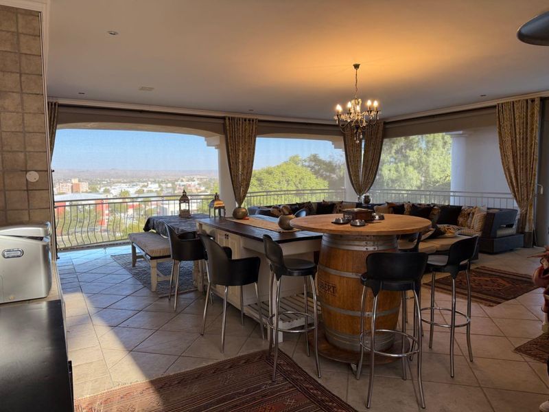 Spacious covered balcony featuring tiled flooring, metal balustrades, and panoramic city views, ideal for outdoor entertaining and relaxation.