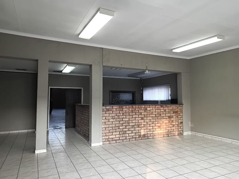 Open plan office space featuring a brick reception counter, tiled flooring, and overhead fluorescent lighting.