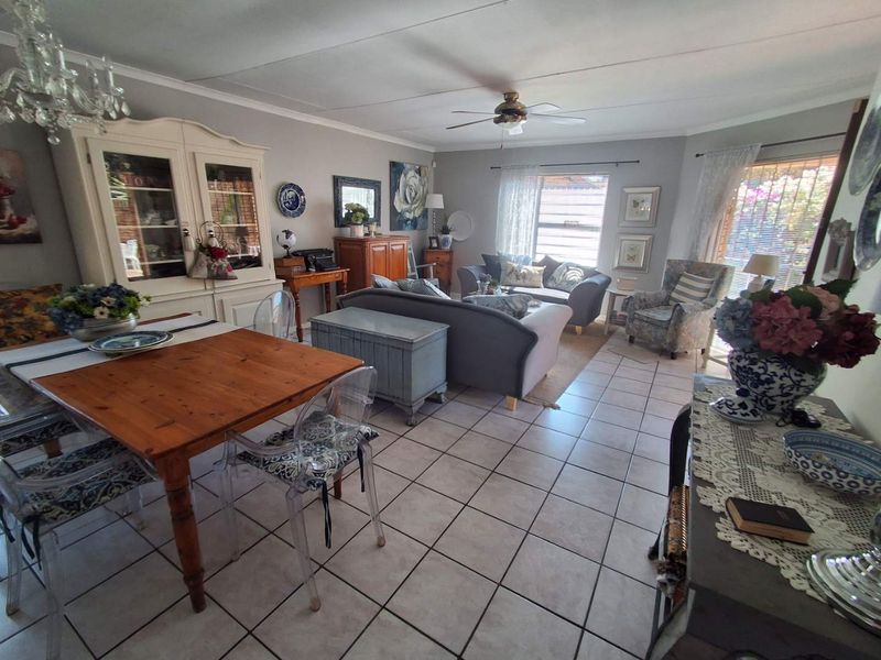 Spacious open-plan living and dining area featuring neutral wall tones, ceramic floor tiles, and a ceiling fan, offering a versatile layout for daily living.