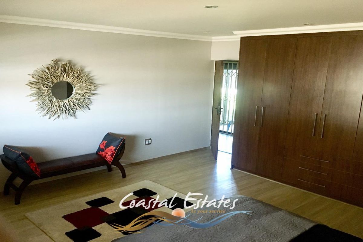 Spacious bedroom featuring built-in wooden cupboards, laminate flooring, and recessed ceiling lighting.