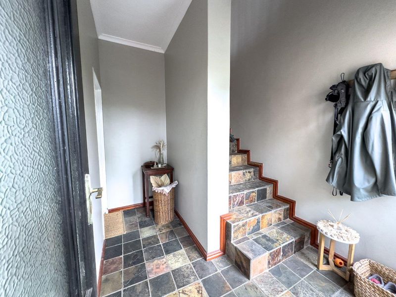 Entrance foyer featuring slate tile flooring and a staircase with timber trim, providing a functional and welcoming transition space.