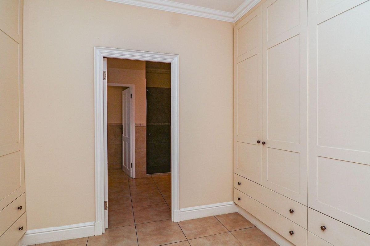 A well-maintained dressing area featuring extensive built-in cabinetry with ample storage, tiled flooring, and direct access to an adjoining bathroom.