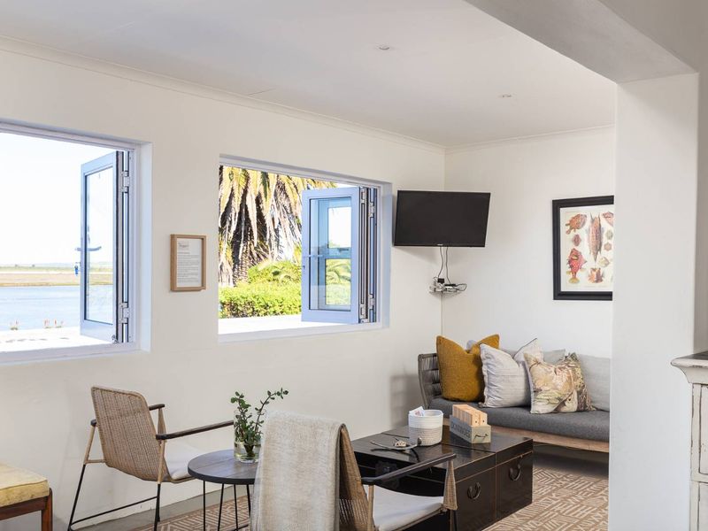 Bright living area featuring large casement windows with scenic water views, neutral walls, and recessed ceiling lighting.