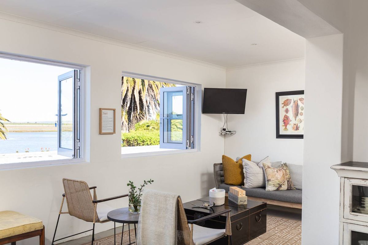 Bright living area featuring large casement windows with scenic water views, neutral walls, and recessed ceiling lighting.