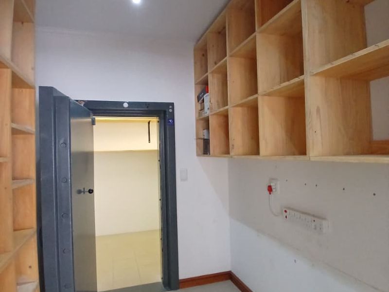 Utility room or secure storage area featuring extensive built-in wooden shelving, tiled flooring, and a heavy-duty steel vault door.