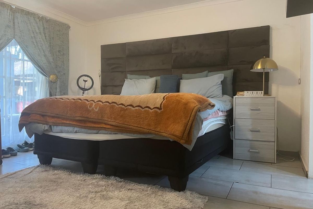 A bedroom featuring tiled flooring and a sliding glass door providing natural light.