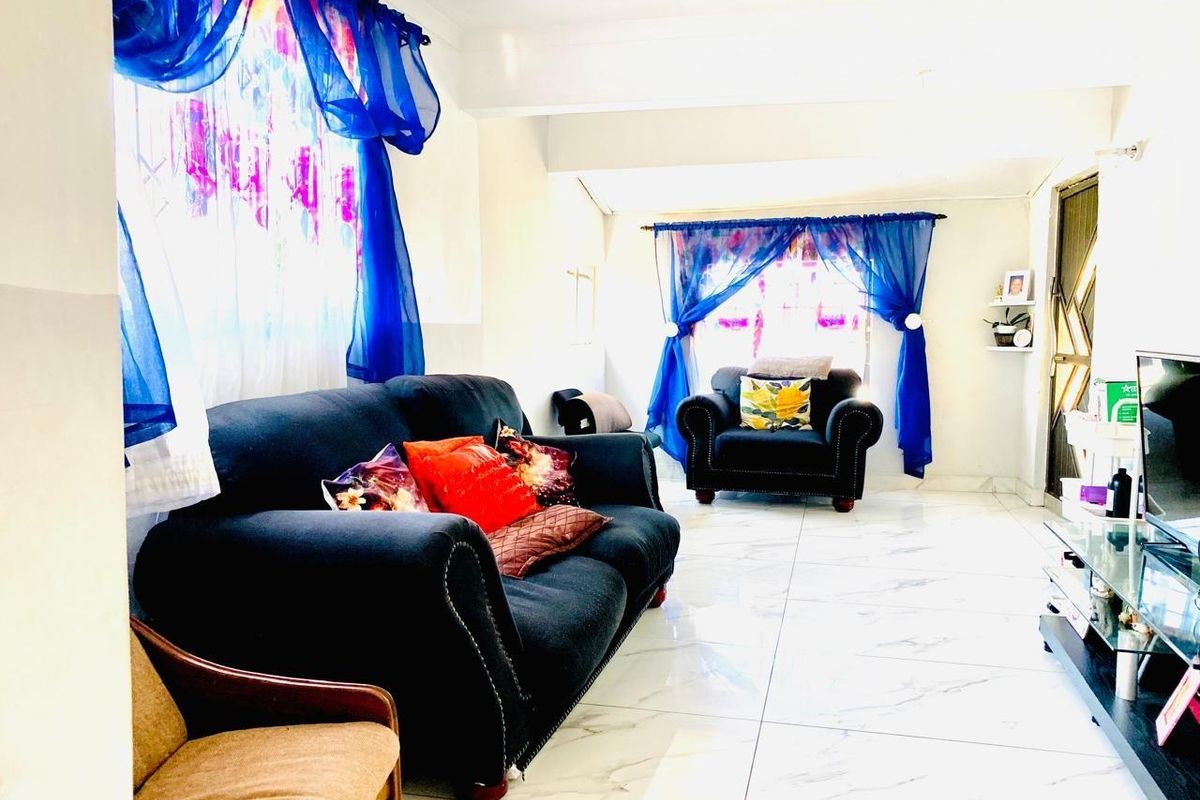A bright living room featuring large-format marble-look floor tiles and decorative window treatments, offering a clean and functional living space.
