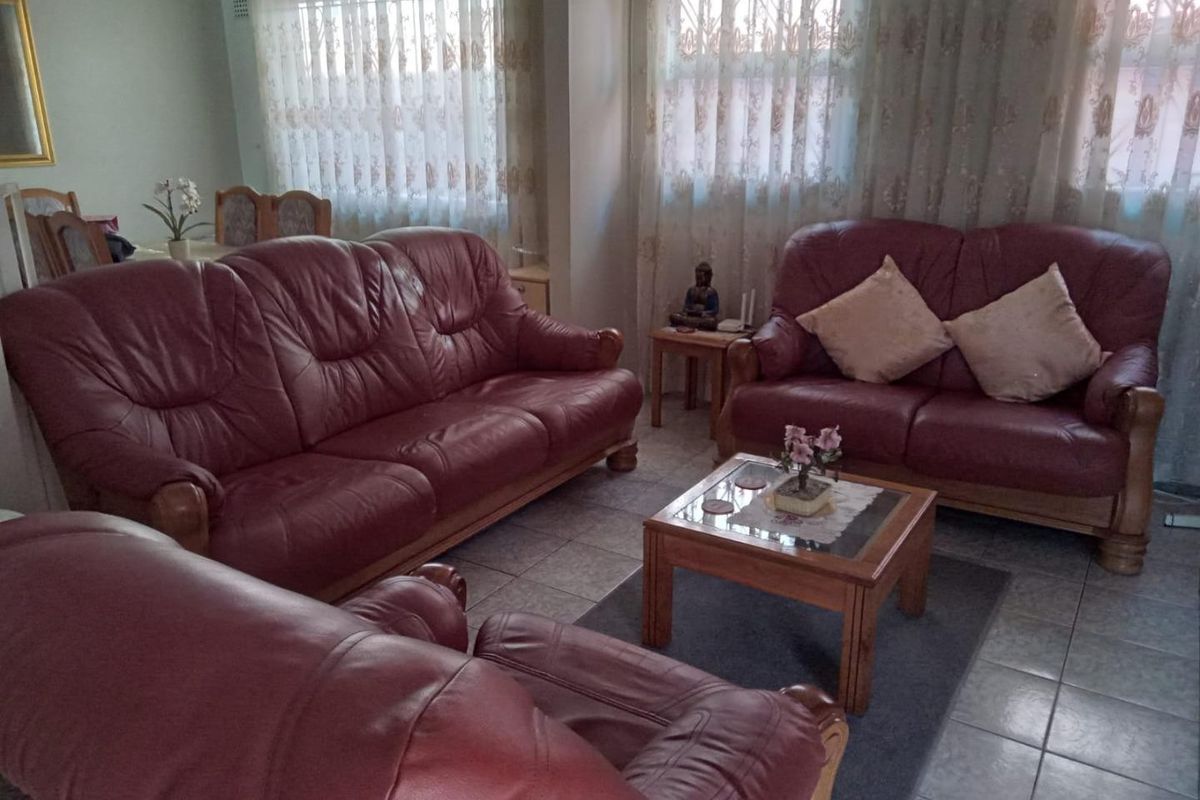 A living room featuring tiled flooring and large windows with security bars, offering a functional space for relaxation.