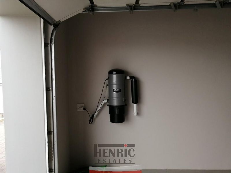 A clean garage space featuring a wall-mounted central vacuum system and a sectional garage door mechanism.