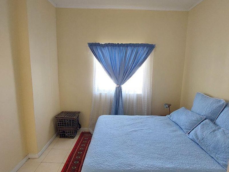 A simple bedroom featuring tiled flooring and a central ceiling light fixture, providing a functional and neutral living space.