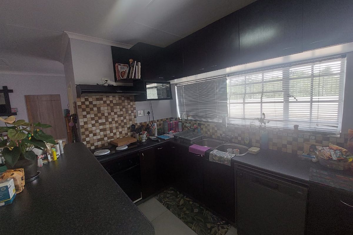 Functional kitchen featuring dark cabinetry, a breakfast bar, mosaic tile backsplash, and integrated sink with window views.
