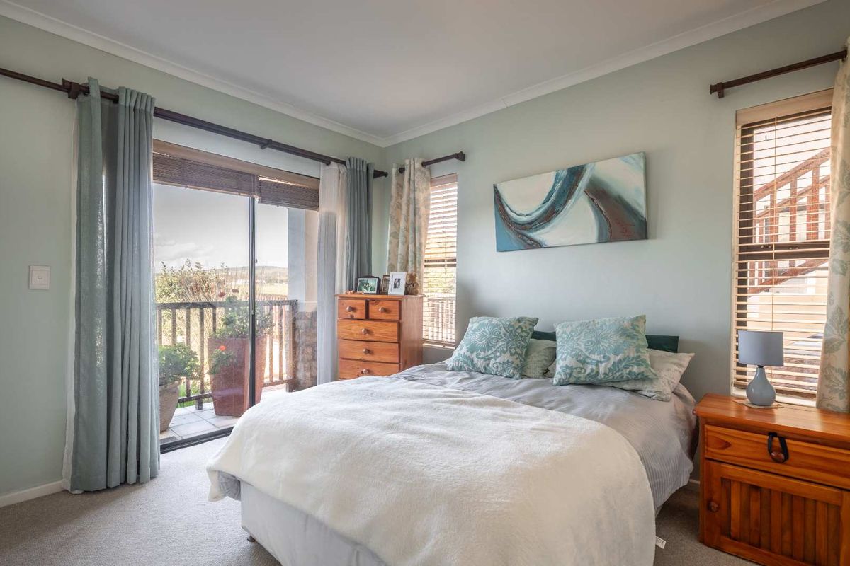 A well-lit bedroom featuring carpeted flooring, neutral wall tones, and a sliding glass door providing direct access to a private balcony.