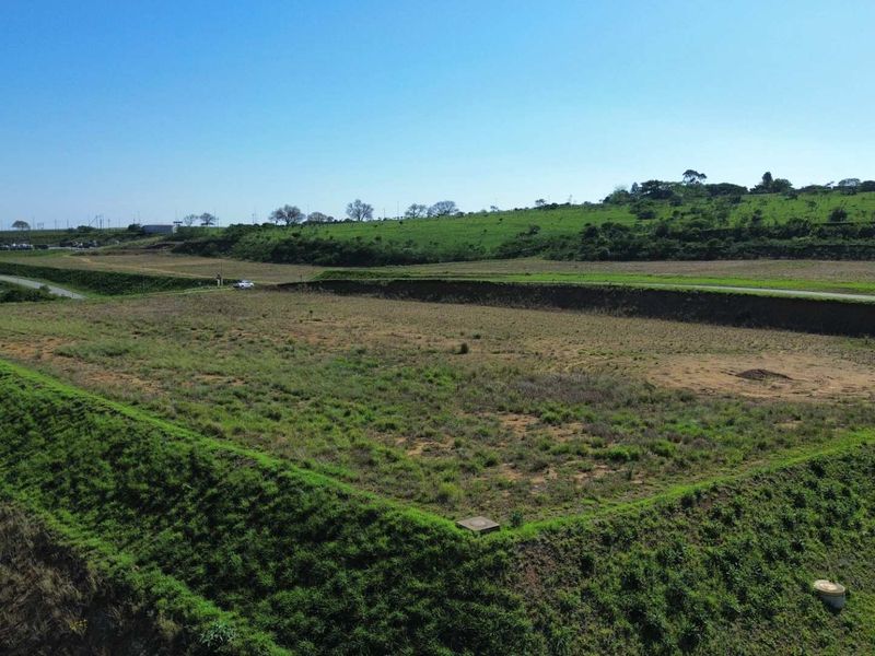 An aerial view of a large, cleared industrial plot featuring significant earthworks and retaining embankments, suitable for future development.