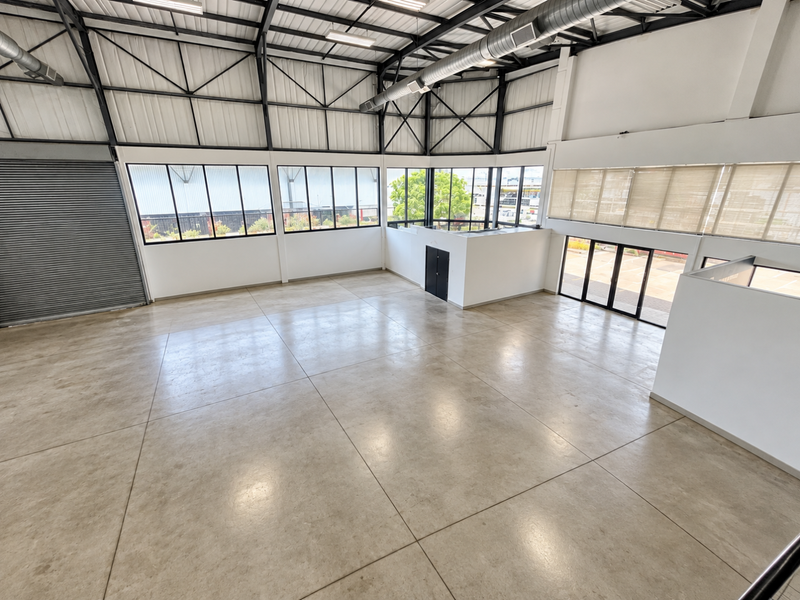 Spacious industrial-style open-plan unit featuring high ceilings with exposed steel trusses, polished concrete floors, and large windows providing ample natural light.