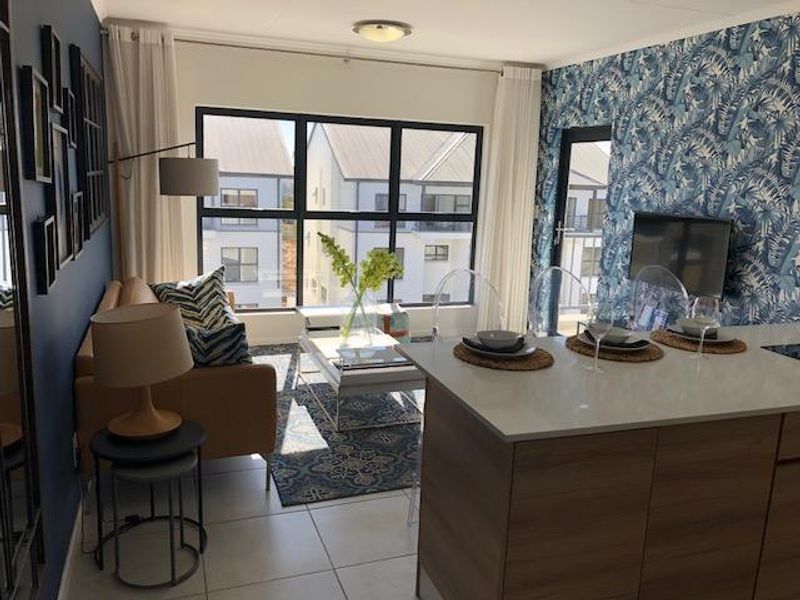 Modern open-plan living area featuring a kitchen island with stone countertops, tiled flooring, and large windows providing ample natural light.