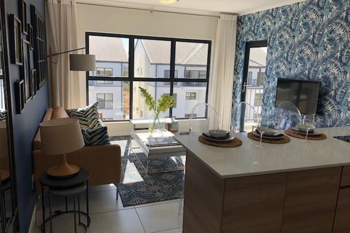 Modern open-plan living area featuring a kitchen island with stone countertops, tiled flooring, and large windows providing ample natural light.
