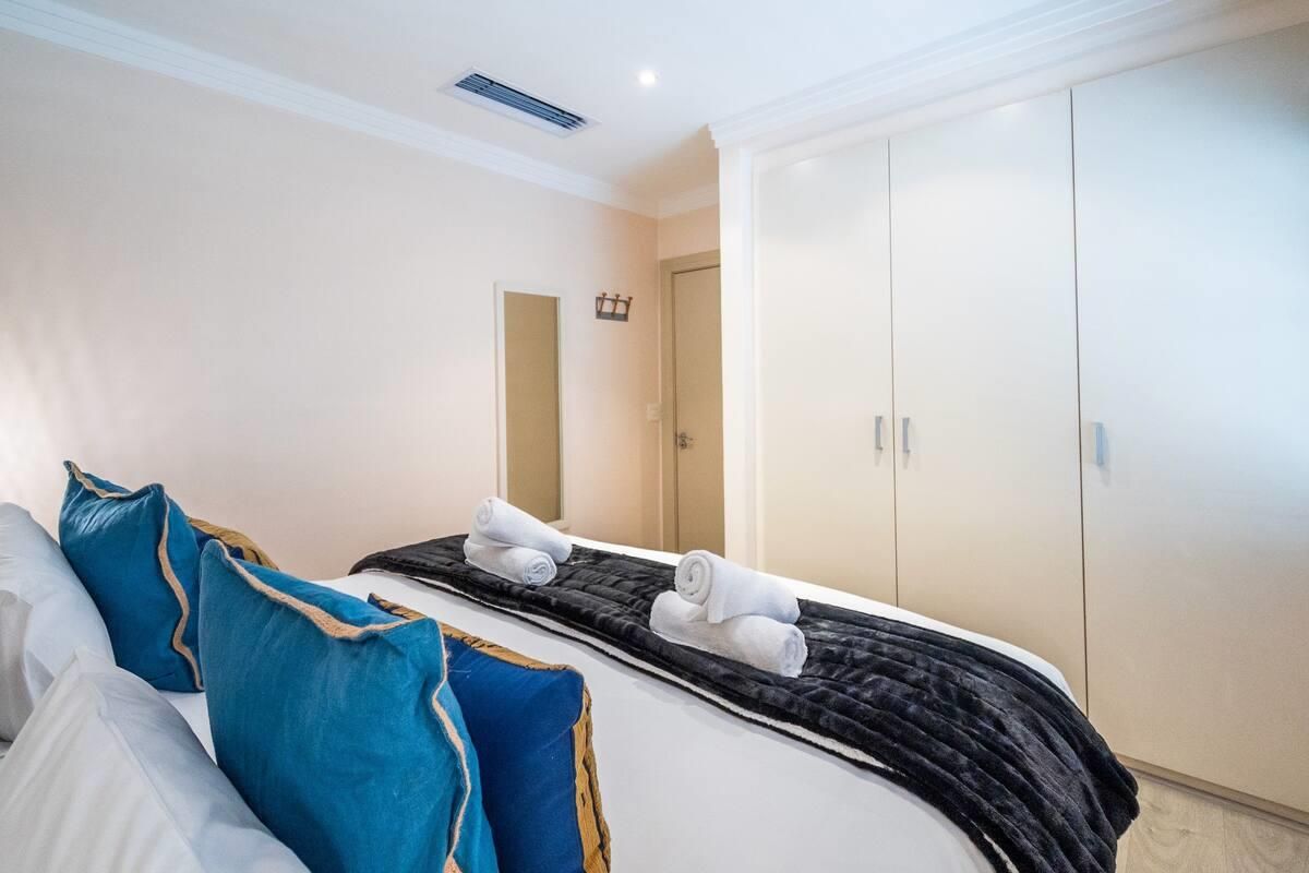 A well-maintained bedroom featuring built-in cupboards, ducted air conditioning, and modern recessed lighting.
