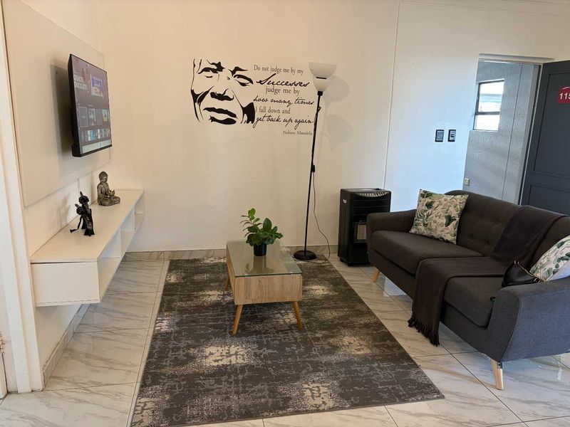 A living room featuring light-colored tiled flooring and a wall-mounted media console, providing a functional and neutral space.