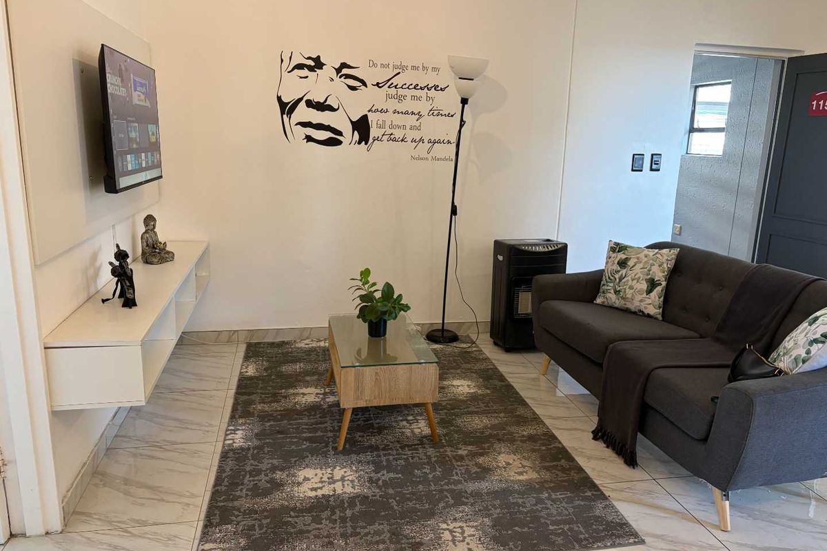 A living room featuring light-colored tiled flooring and a wall-mounted media console, providing a functional and neutral space.